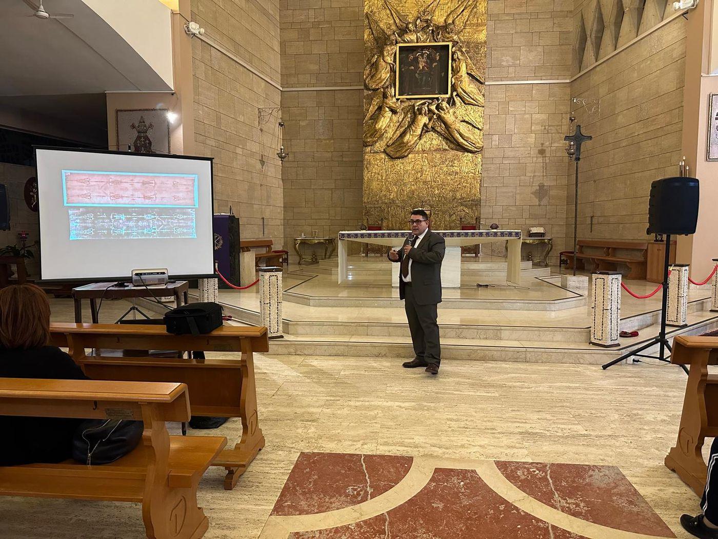 Leone Massimo Occhiuto durante la conferenza davanti al presbiterio della Basilica dell'Eremo, accanto allo schermo con le immagini della Sindone