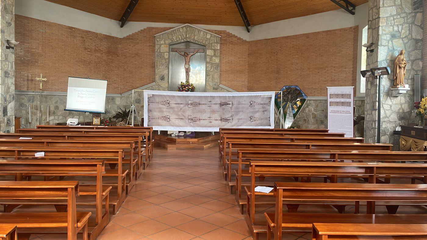 Navata della parrocchia di Santa Croce a Santa Venere con la copia della Sindone davanti all'altare e lo schermo della conferenza